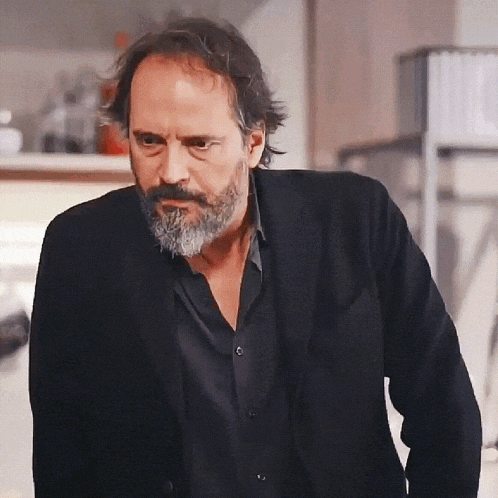 a man with a beard is wearing a black jacket and a black shirt