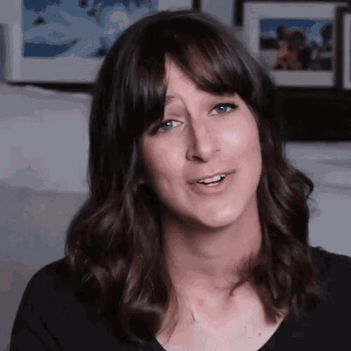 a woman with brown hair and blue eyes is smiling