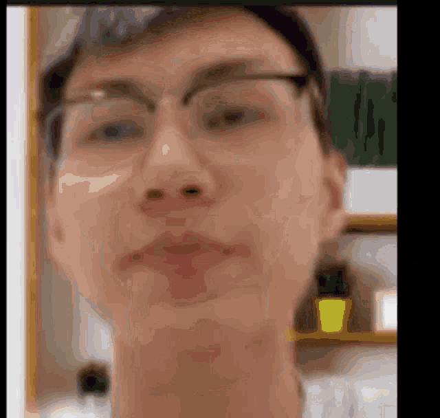 a blurry picture of a man wearing glasses and a white shirt .