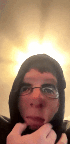 a man wearing glasses and a black hoodie is making a face