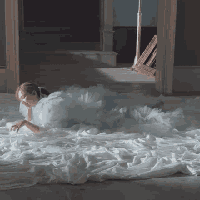 a woman in a blue dress is laying on a bed