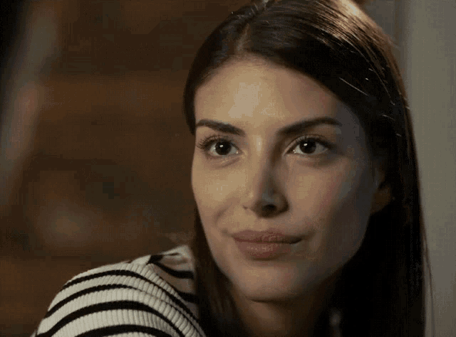 a close up of a woman 's face with a black and white striped shirt