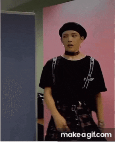 a man wearing a black beret and a plaid skirt is standing in a room .