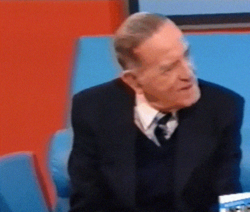 a man in a suit and tie is sitting in front of a blue chair