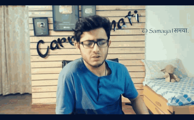 a man wearing glasses stands in front of a wall that says caprinati