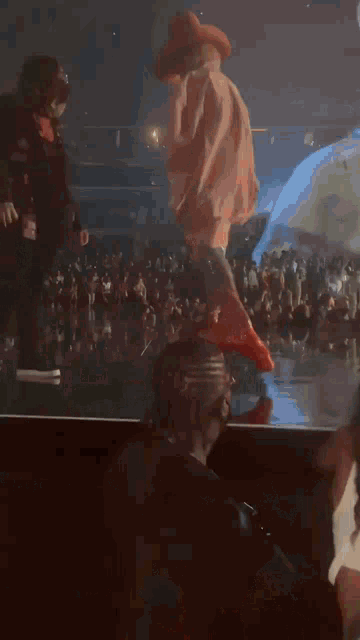 a man in a cowboy hat stands on a stage in front of a crowd of people