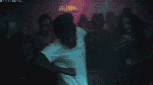 a man in a white t-shirt is dancing in a crowded room .