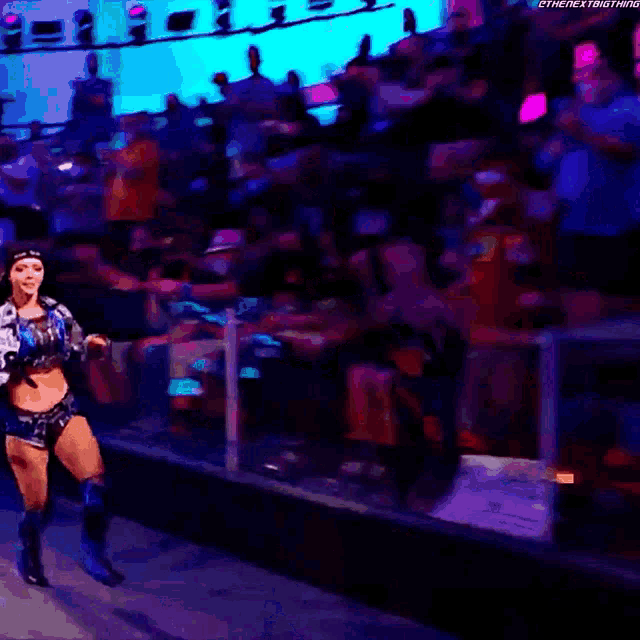 a woman wearing a hat and a denim jacket is dancing in a dark room .