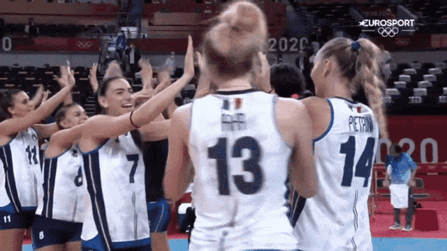 a group of female volleyball players are giving each other a high five .