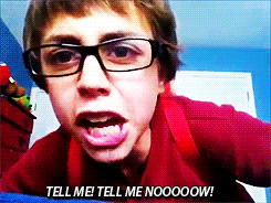 a boy wearing glasses is making a funny face and says tell me tell me nooooow