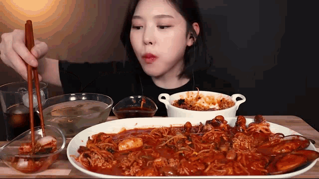 a woman is eating a plate of food with chopsticks ..