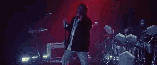 a man is singing into a microphone in a dark room in front of a light .
