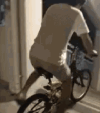 a man in a white shirt is riding a bike in a room .