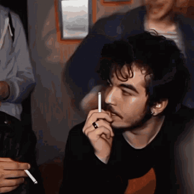 a man is smoking a cigarette in a dark room