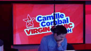 a man sitting in front of a screen that says virgin radio