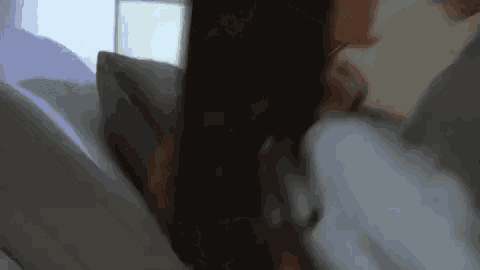 a woman is laying in bed with a pillow in her hand .