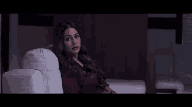 a woman is sitting on a white couch and looking at something