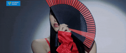 a woman in a red dress holds a red fan in front of her face in front of a blue sign that says lip private works