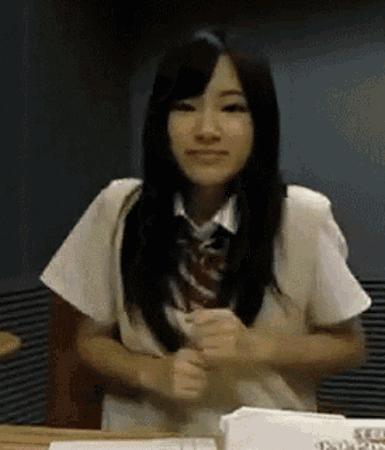 a girl in a school uniform is standing in front of a table with a sign that says ' tokyo ' on it