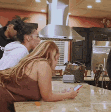 a woman is laying on a counter looking at her cell phone