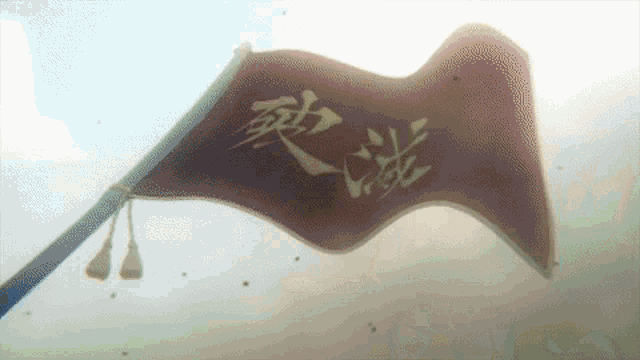 a red flag with chinese characters on it is waving in the wind