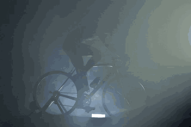 a silhouette of a person riding a bike in a dark room