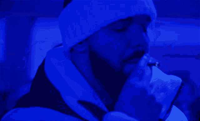 a person wearing a white headband is smoking a cigarette in a blue room