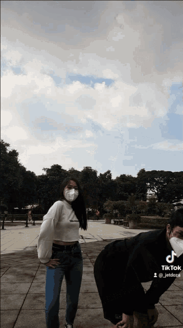 a woman wearing a mask stands next to a man wearing a black shirt and black shorts