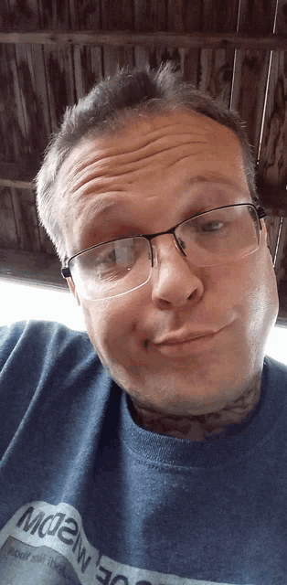 a man wearing glasses and a blue shirt that says mc2w on it
