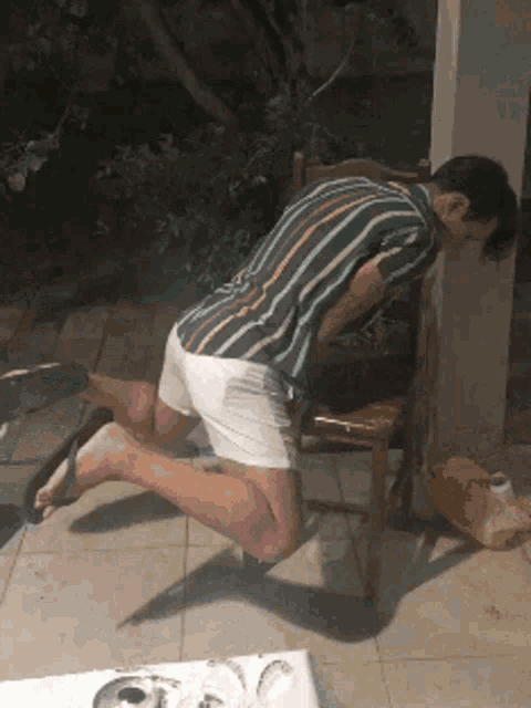 a man in a striped shirt is kneeling down on the floor