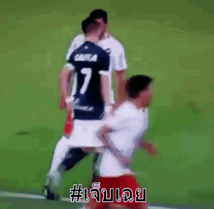 a soccer player is laying on his back on the field while another player holds his leg up .