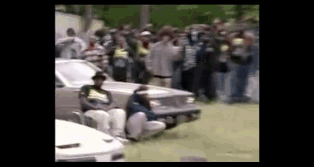 a group of people are standing around a car in a field .