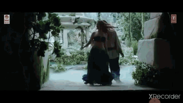 a woman in a green dress is walking with a man in a white robe .