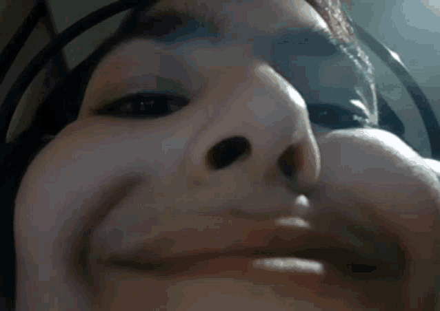 a close up of a person 's face with headphones on and making a funny face .