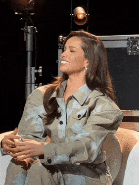 a woman in a floral jacket is sitting on a couch smiling
