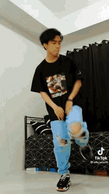 a young man in a black shirt and blue jeans is dancing .
