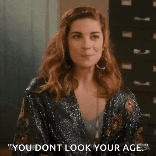 a woman in a sequined jacket is making a funny face and says `` you don 't look your age '' .