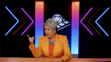 a woman in a yellow jacket is sitting at a table with her hands outstretched