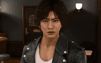 a man wearing a leather jacket and a white tank top is looking at the camera