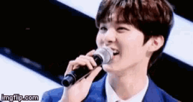 a young man is singing into a microphone with imgflip.com written below him
