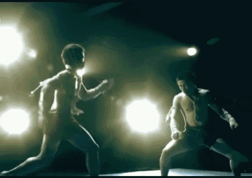 two men are boxing in a dark room with lights on