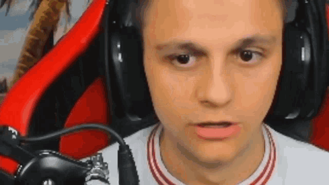 a man wearing headphones is making a funny face while sitting in a red chair .