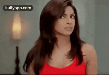 a woman in a red tank top is making a funny face .