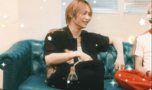 a young man sits on a blue couch with a bottle of water in his lap