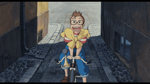 a boy wearing glasses and a yellow shirt is riding a bike down a cobblestone street