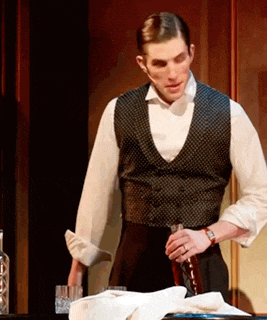 a man in a tuxedo is holding a bottle of wine