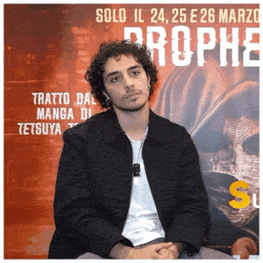 a man is sitting in front of a poster that says solo il 24 25 e 26 marzo