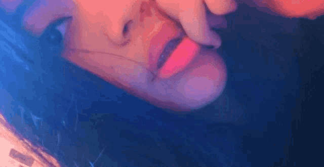 a close up of a woman 's face with a red lip and a blue background .
