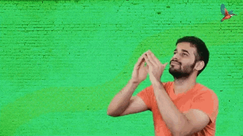 a man covering his mouth with his hands in front of a green wall that says oolala leohhh