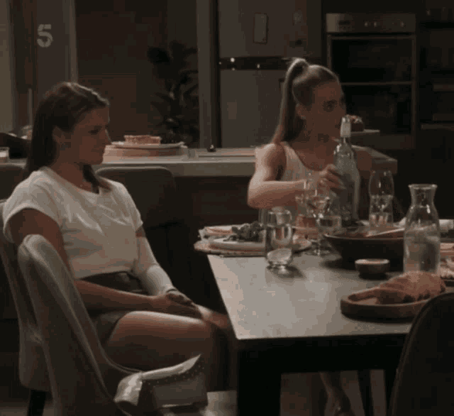two women sit at a table with the number 5 on the wall